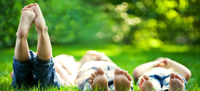 Bambini sdraiati sull'erba con i piedi nudi all'aria